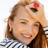 Kenneth Jay Lane Gold Chubbie hoop earrings on model in stripe shirt also wearing a red enamel kenneth jayl lane ring